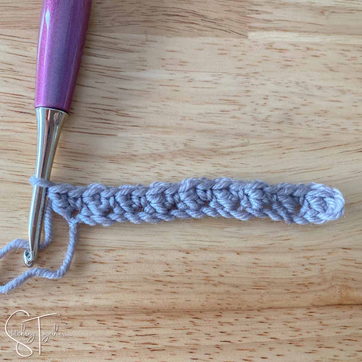 hook and yarn showing row 1 of suzette stitch crochet completed