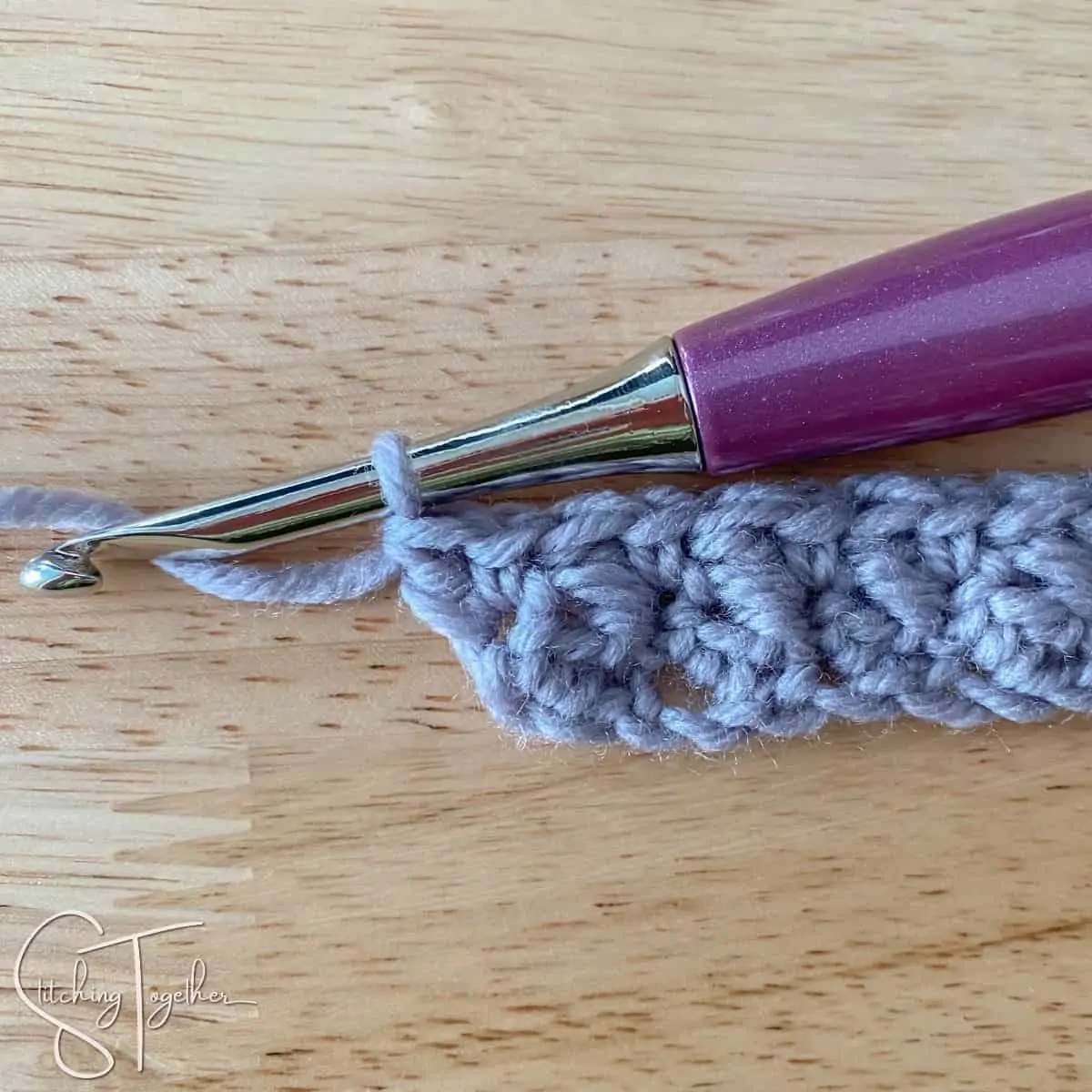 crochet hook and yarn showing row 2 of suzette stitch completed