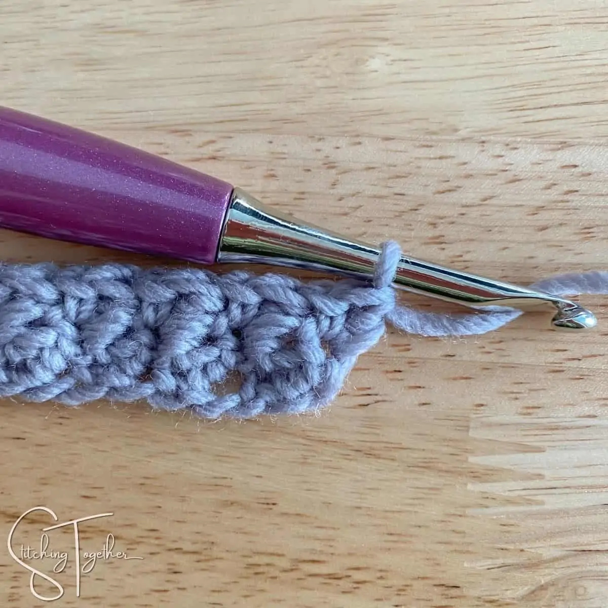 crochet hook and yarn showing row 2 of suzette stitch completed