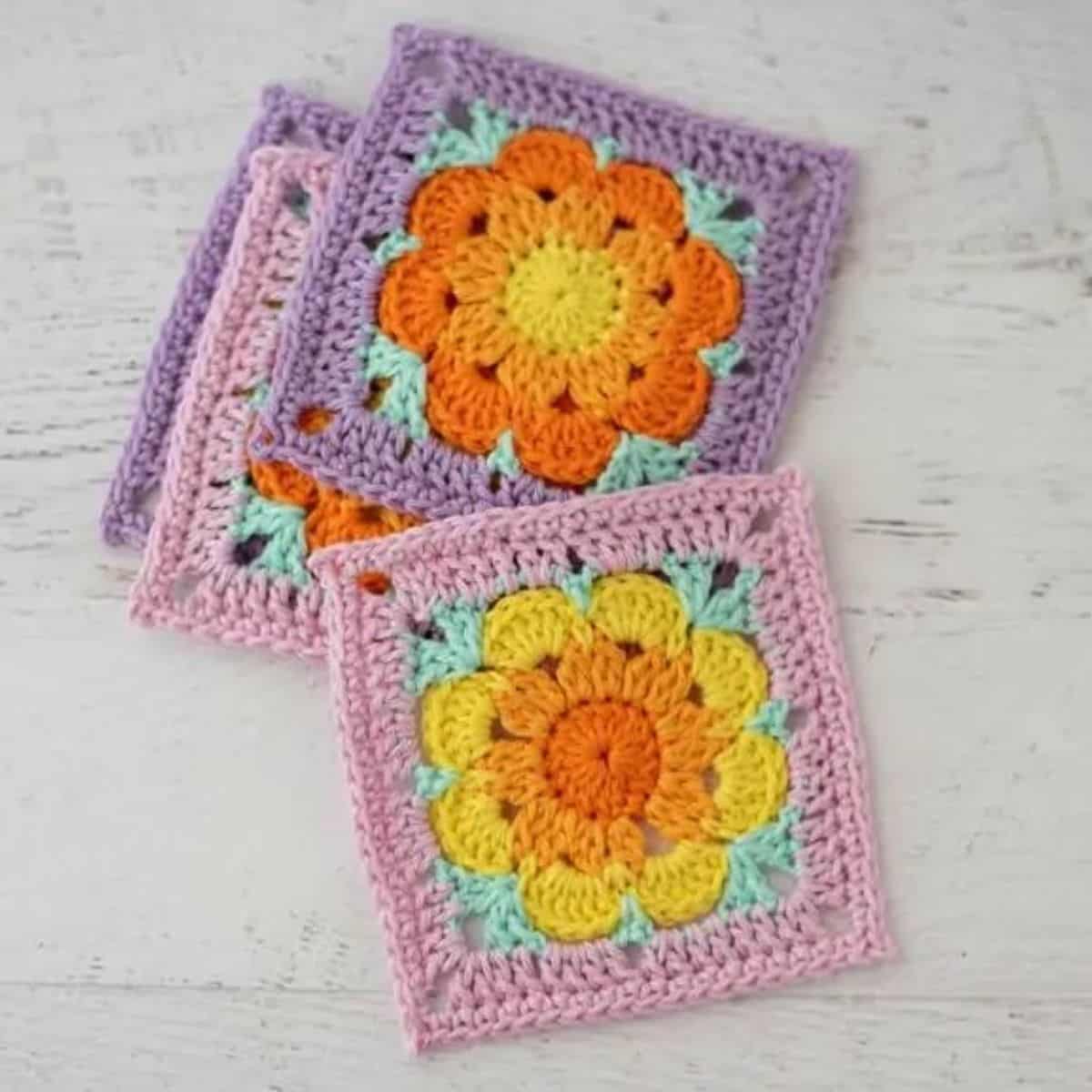colorful square crochet coasters with a flower motif in the center