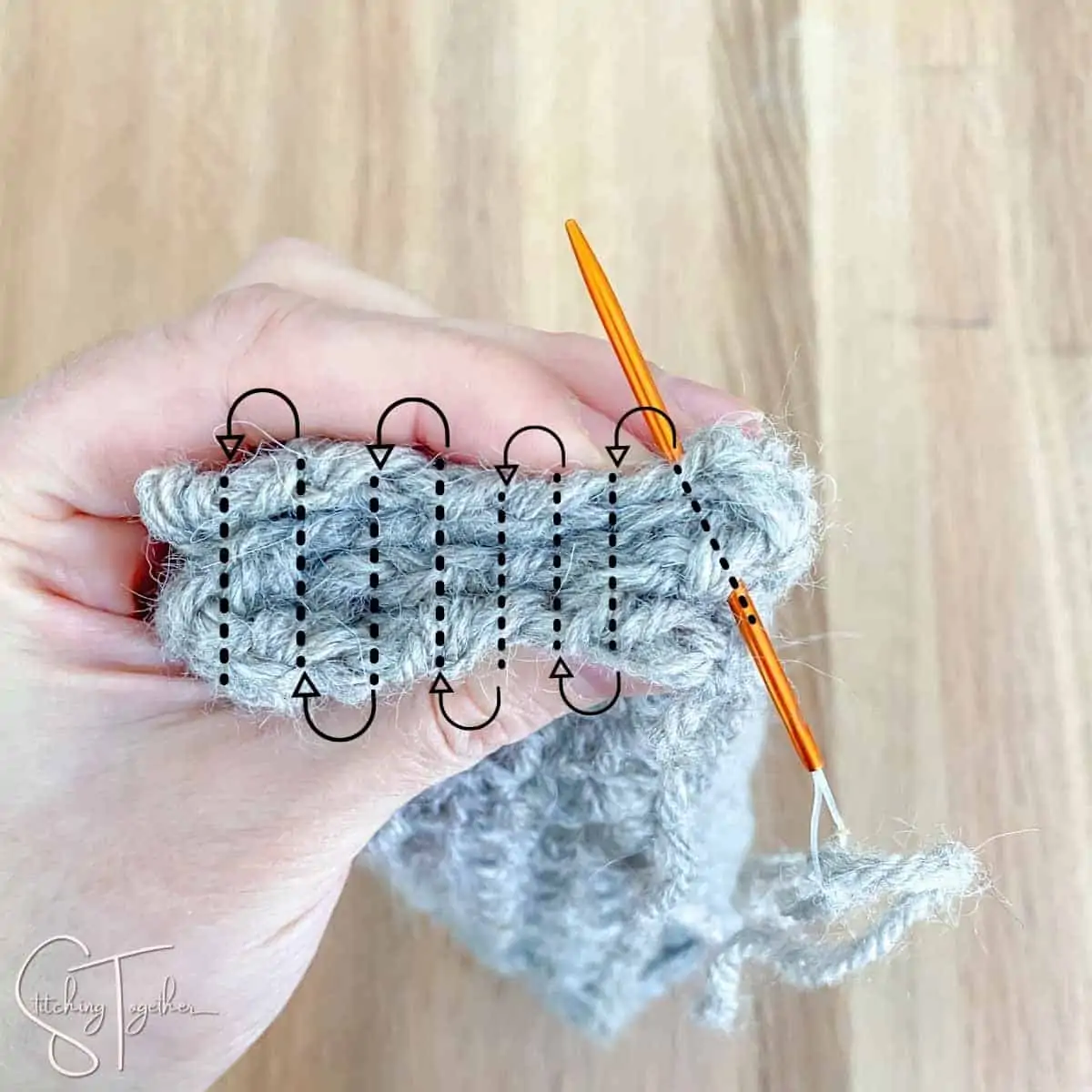 folded crochet rectangle with arrows drawn showing how to sew together to make a twisted ear warmer