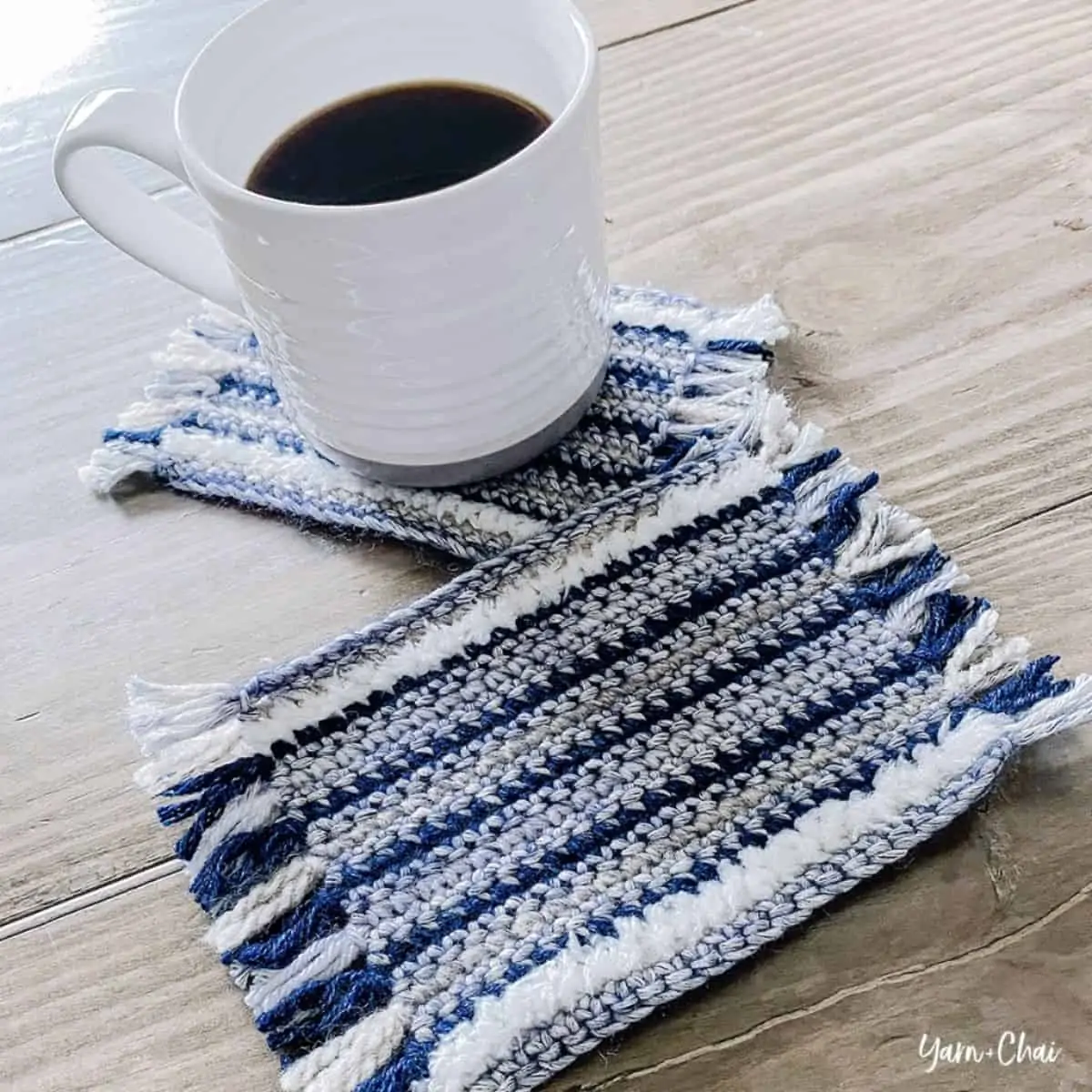 coffee cup and multicolored striped crochet coasters on a table