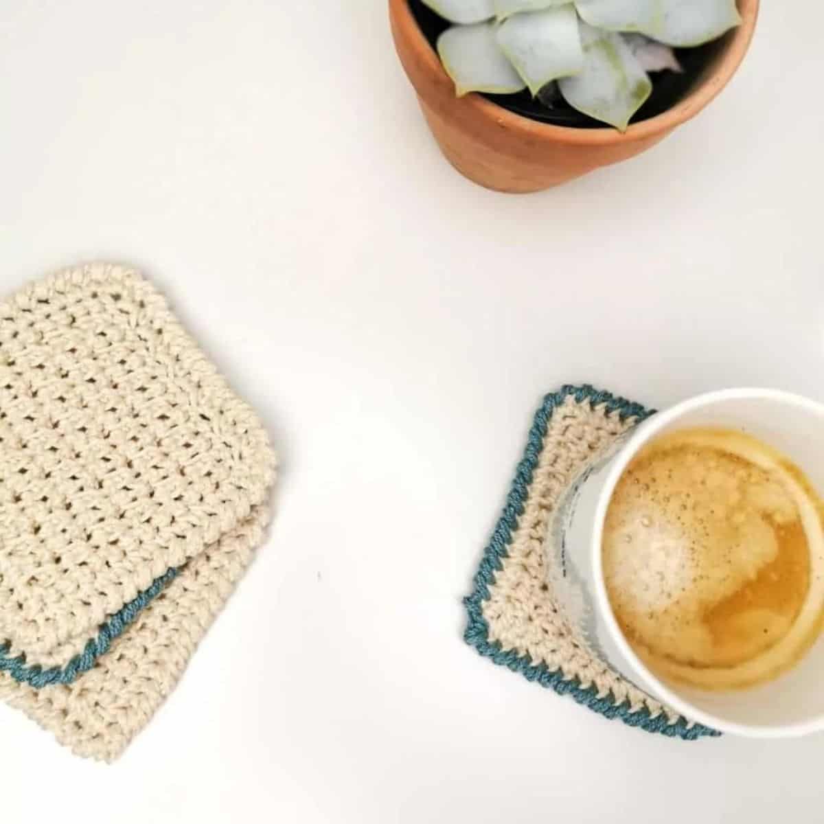 tea cup, plant, and crochet coasters on a flat surface