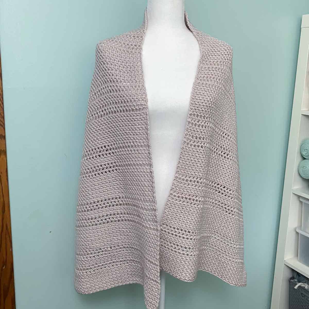 simple crochet shawl in a neutral color draped over the shoulders of a mannequin
