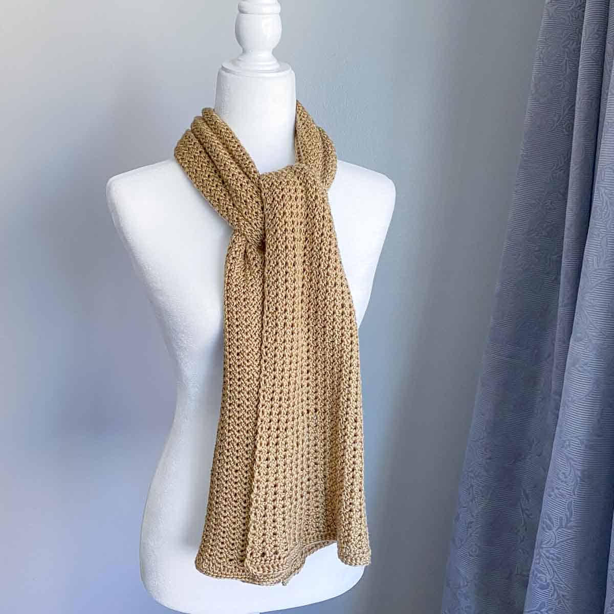 golden colored crochet scarf wrapped on a mannequin