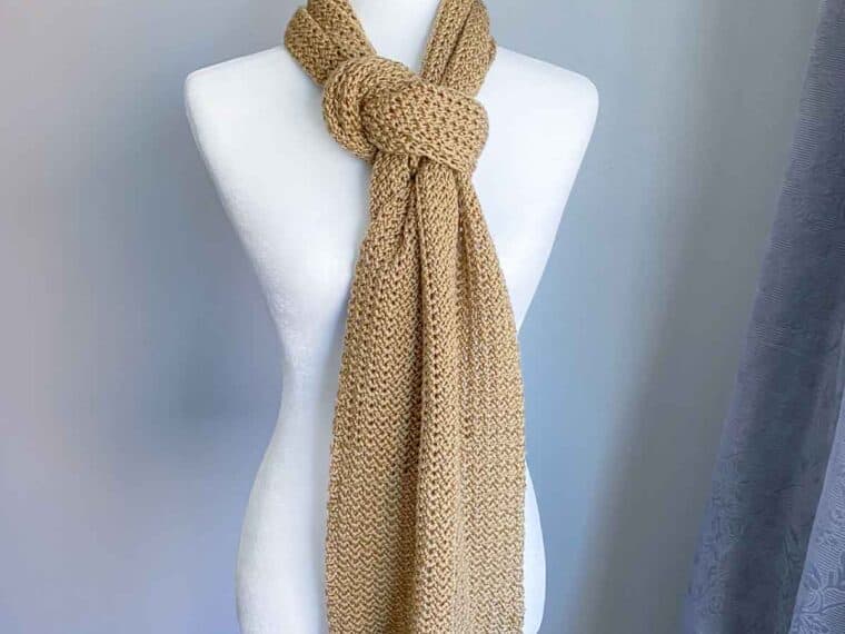 golden colored crochet scarf knotted at the neck of a headless mannequin