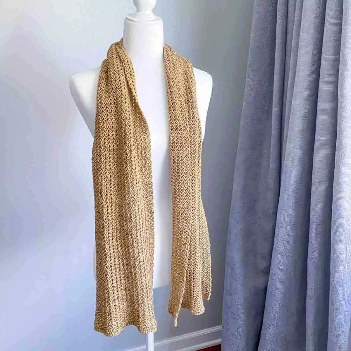 flowy crochet scarf in a yellow golden color draped on the shoulders of a mannequin
