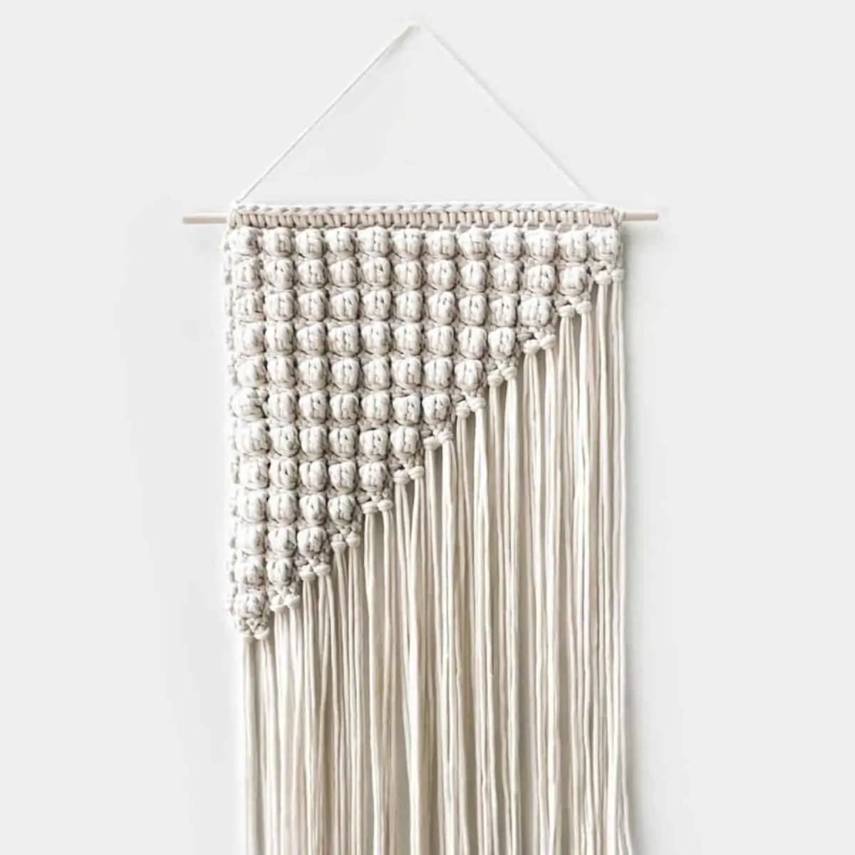 triangular crochet wall hanging made with bobbles and long fringe