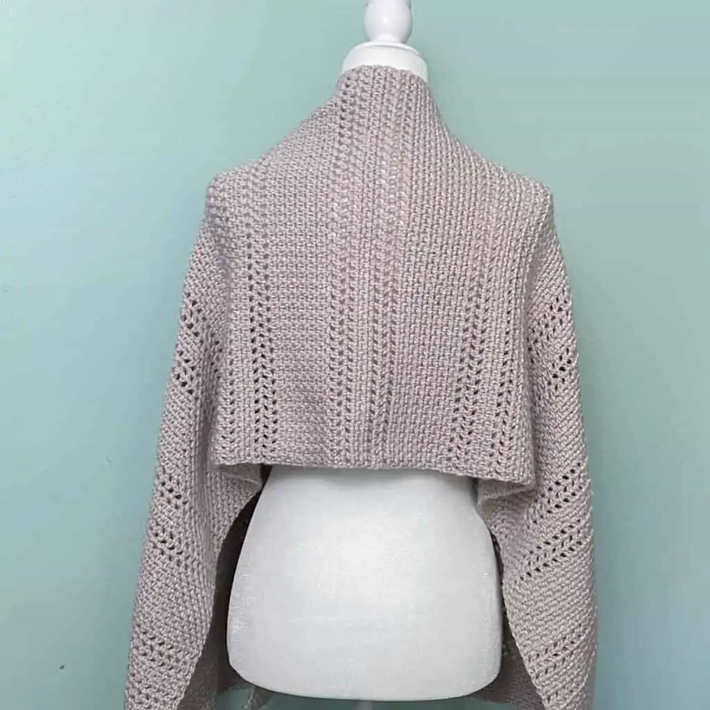 view of the back of a crochet wrap draped across the shoulders of a mannequin
