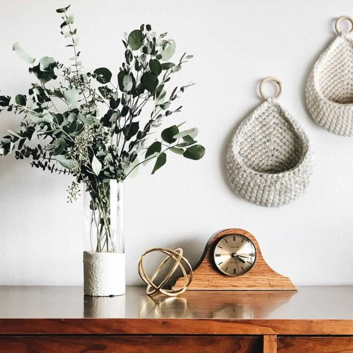 styled buffet with a plant, clock, and crochet hanging baskets