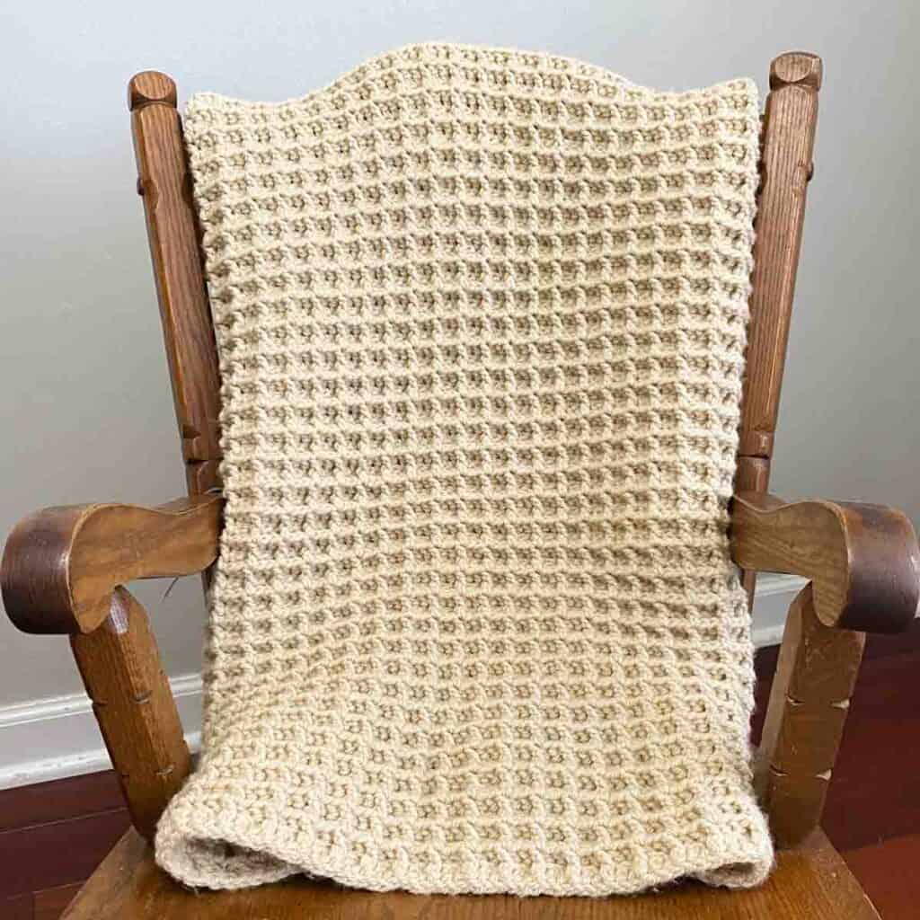 waffle stitch crochet blanket folded over the back of a small rocking chain