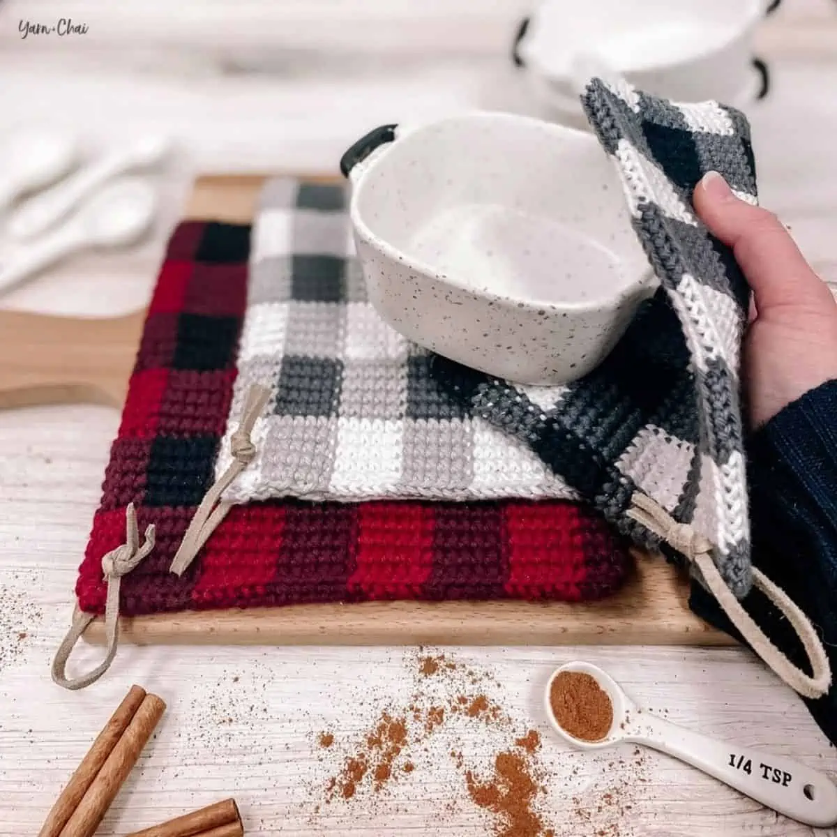 red and black and a gray and black buffalo check potholders with one holding an empty dish