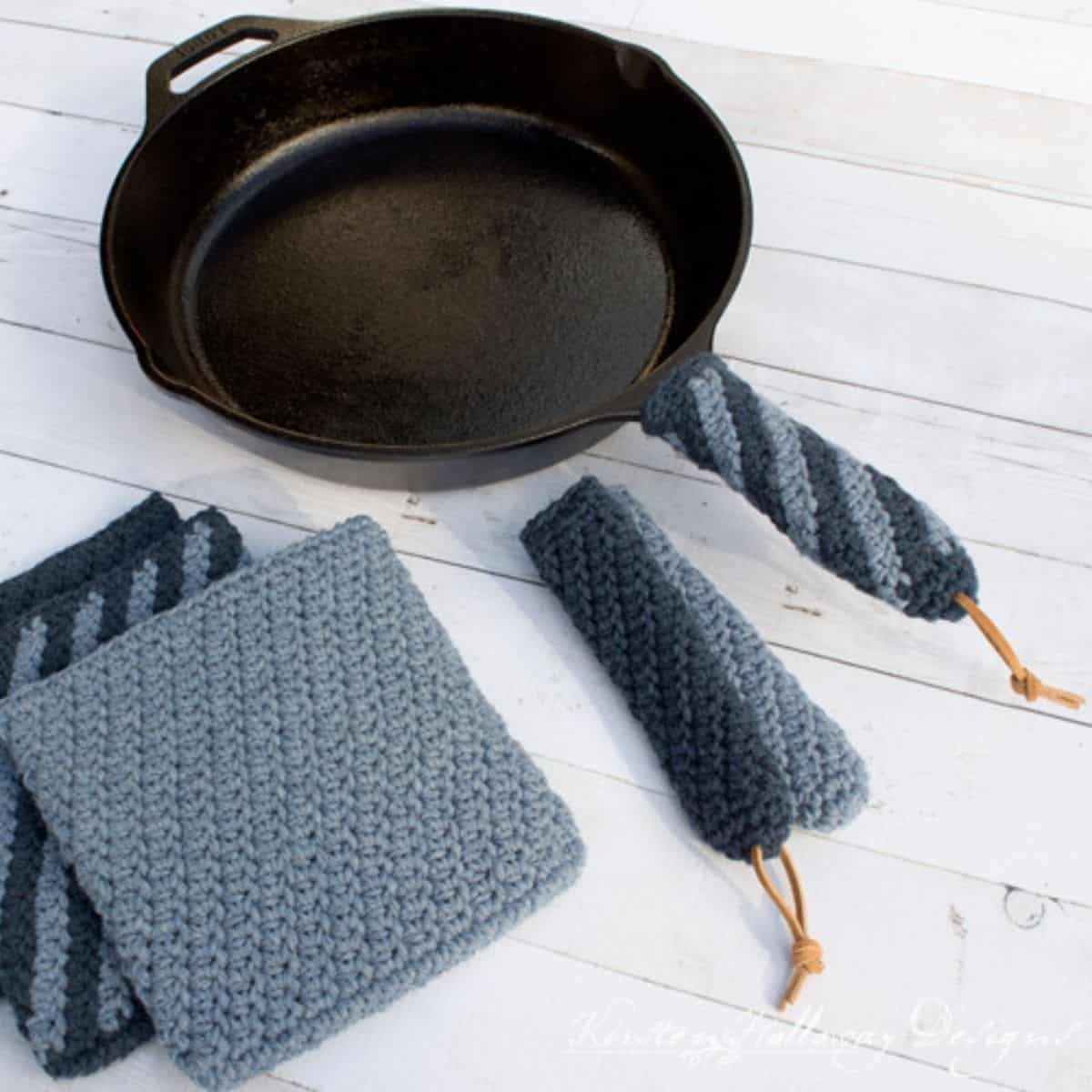 cast iron pan with a crochet handle covers and potholders sitting nearby