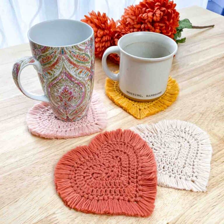 two mugs sitting on crochet heart coasters that have fringe