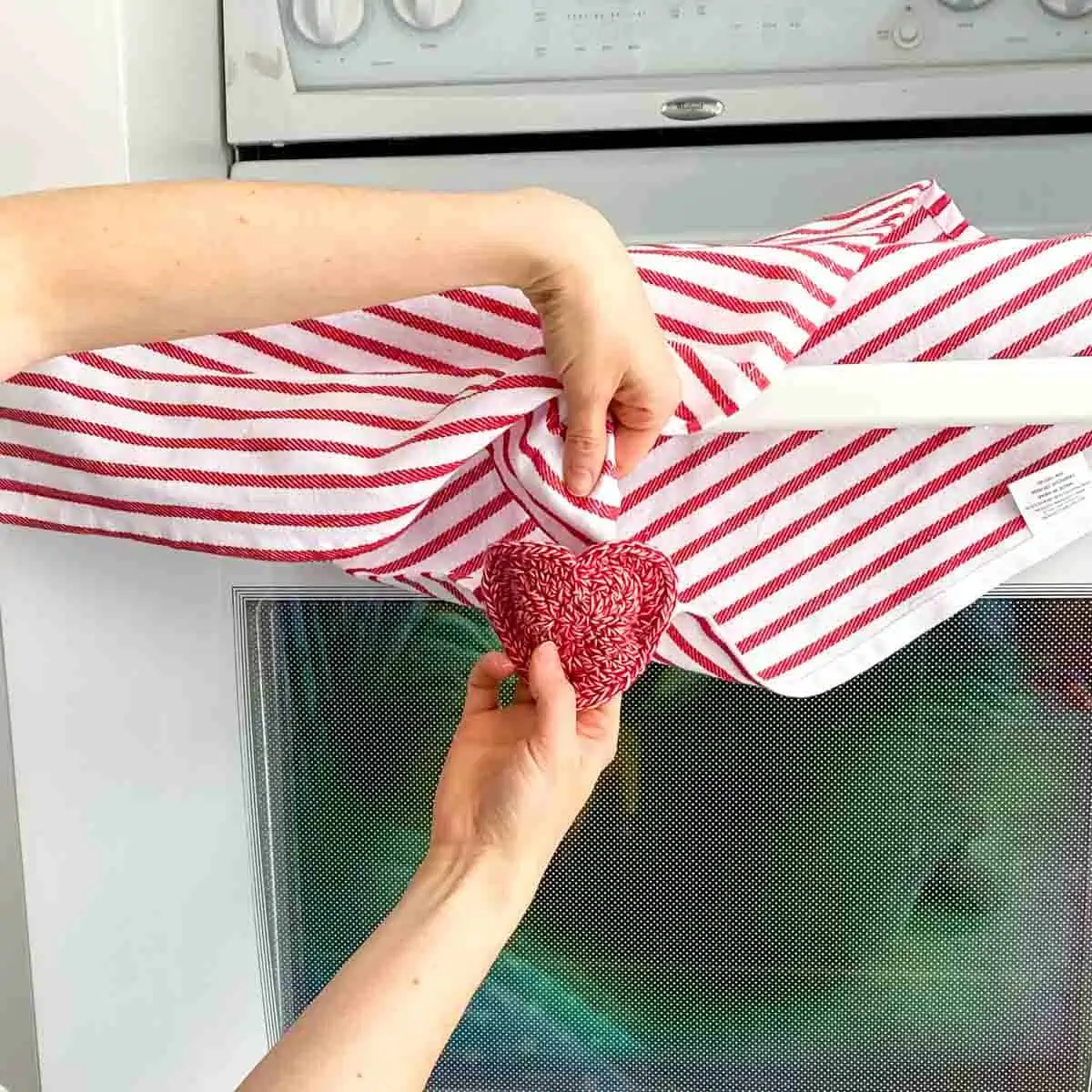 showing how to pull a dish towel through the crochet towel topper heart