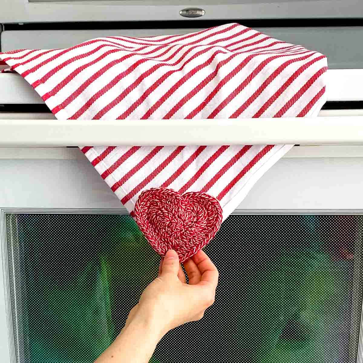 passing a dishtowel with a crochet towel topper through the bar of an oven