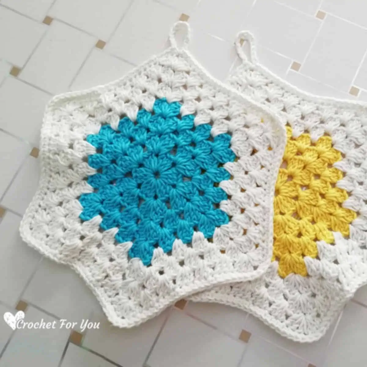 two crochet hexagon potholders one with a yellow center and one with a blue center