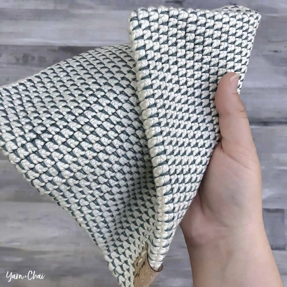 blue and white crochet potholder being held in a hand 