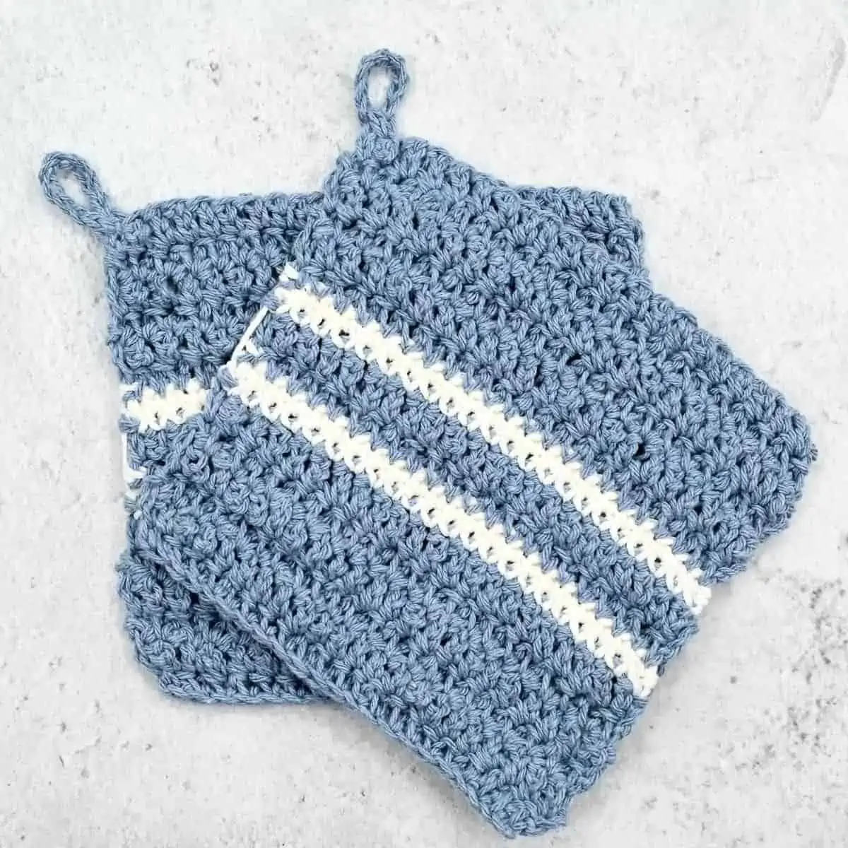 blue crochet potholders with white stripes laying flat on a counter