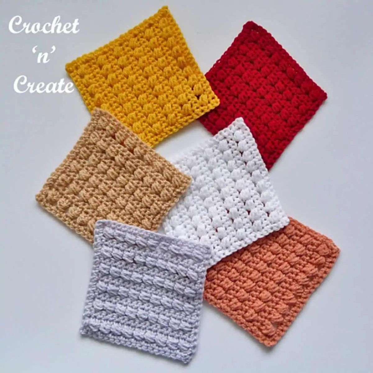 a pile of 6 crochet granny squares that a solid color but have stripes of bobble stitches