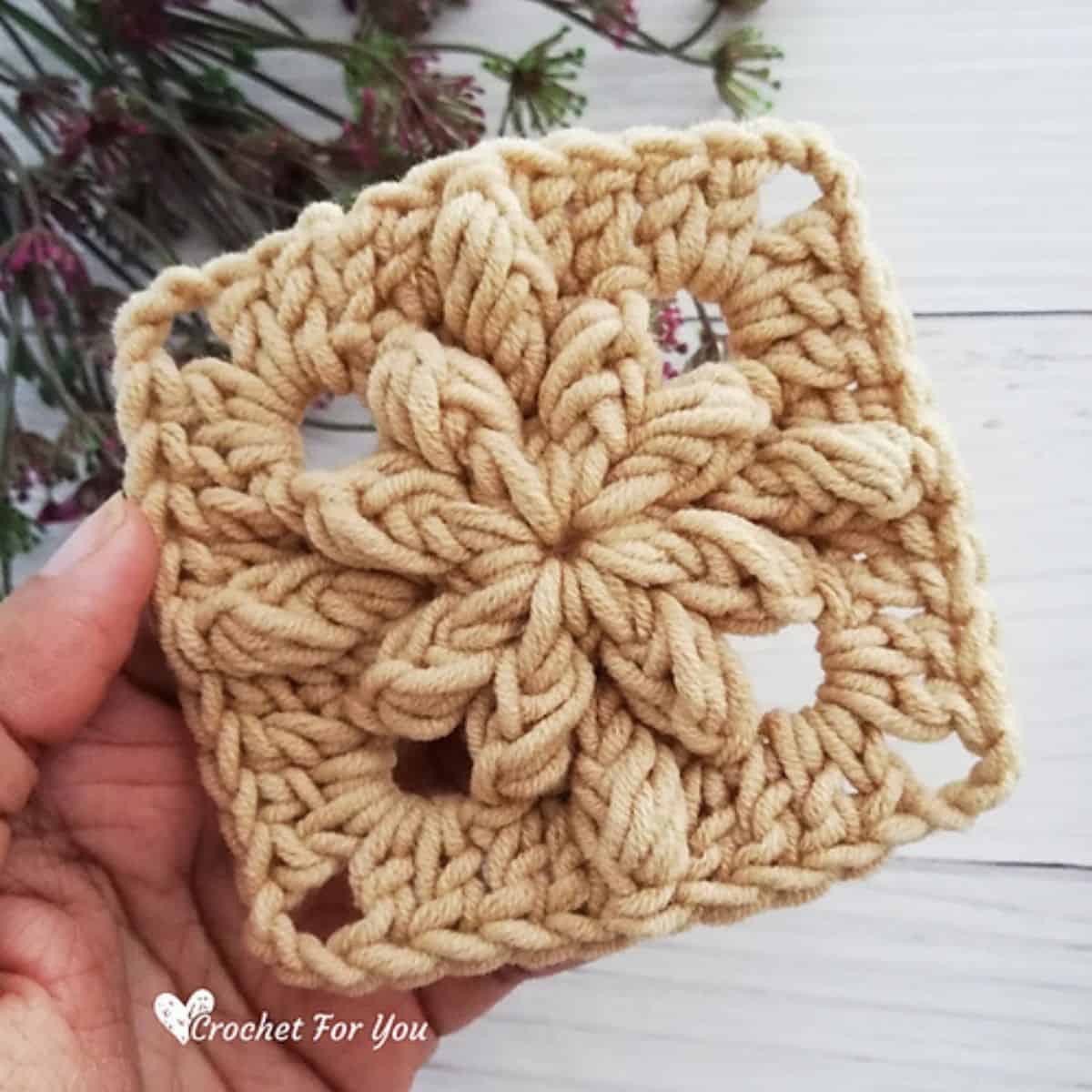 small crochet granny square with a raised crochet flower motif in the center