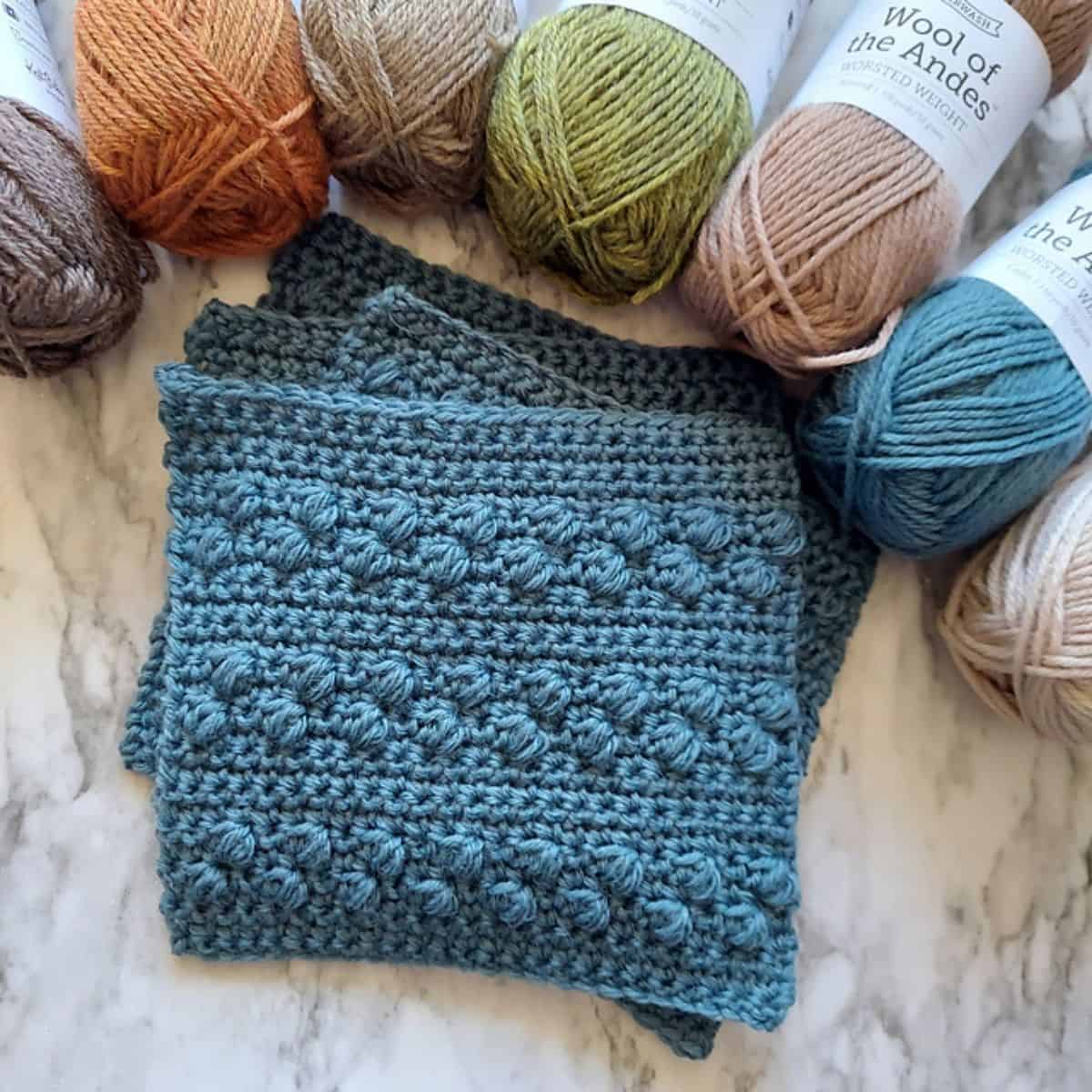 solid granny squares with skeins of yarn surrounding them