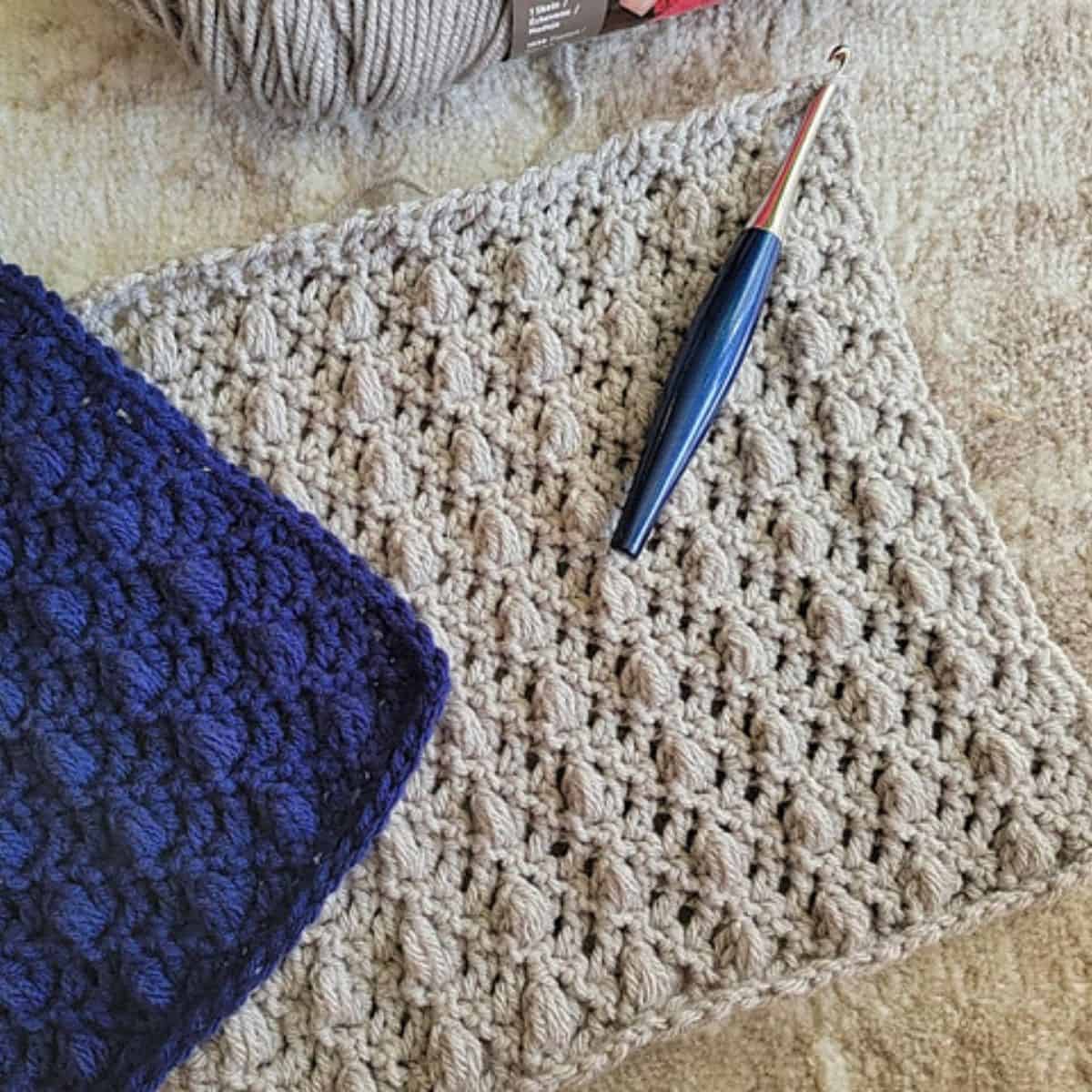 solid and textured crochet squares with a crochet hook sitting on top of one of the squares