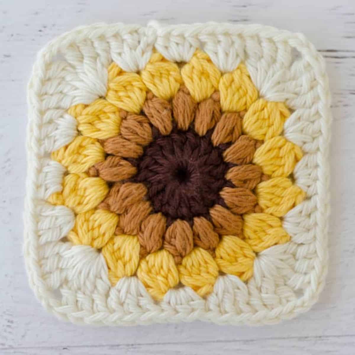 crochet granny square with a sunflower motif in the middle