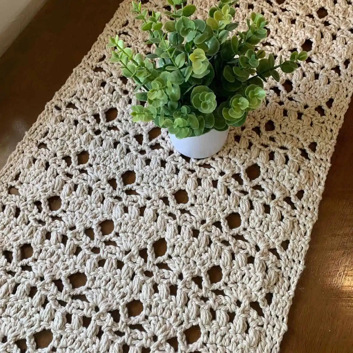 small vase of greenery sitting on a lace crochet table runner