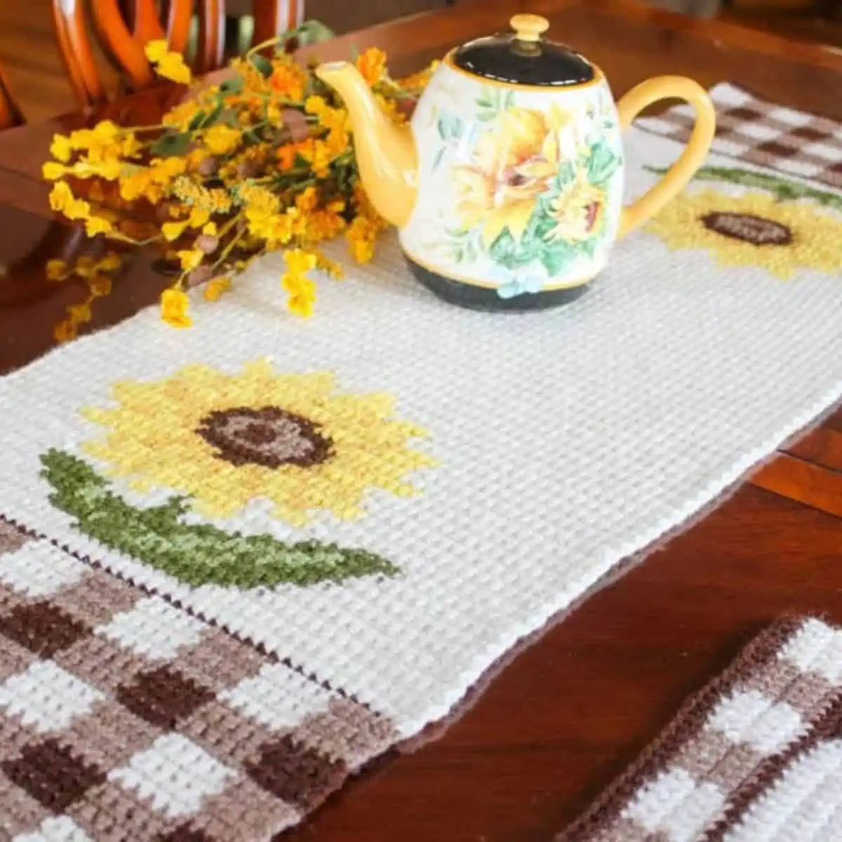 table runner with a gingham and sunflower pattern with a teapot sitting on it
