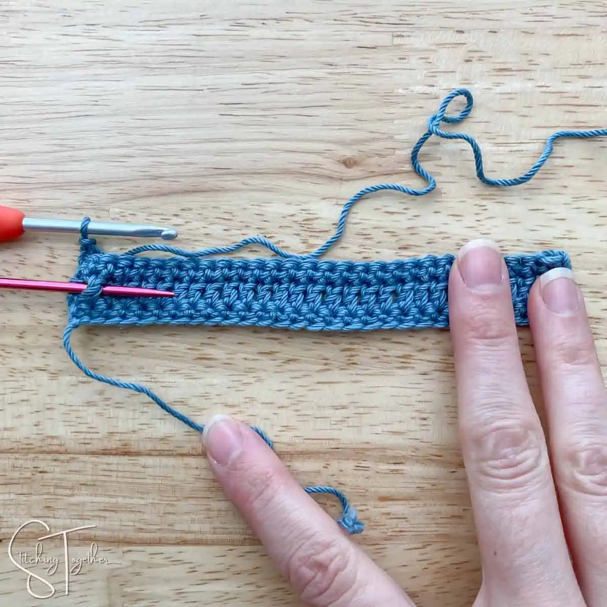 left crochet fabric swatch with a needle around a post stitch showing where to put the next stitch