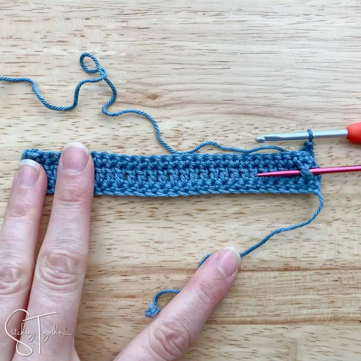crochet fabric swatch with a needle around a post stitch showing where to put the next stitch