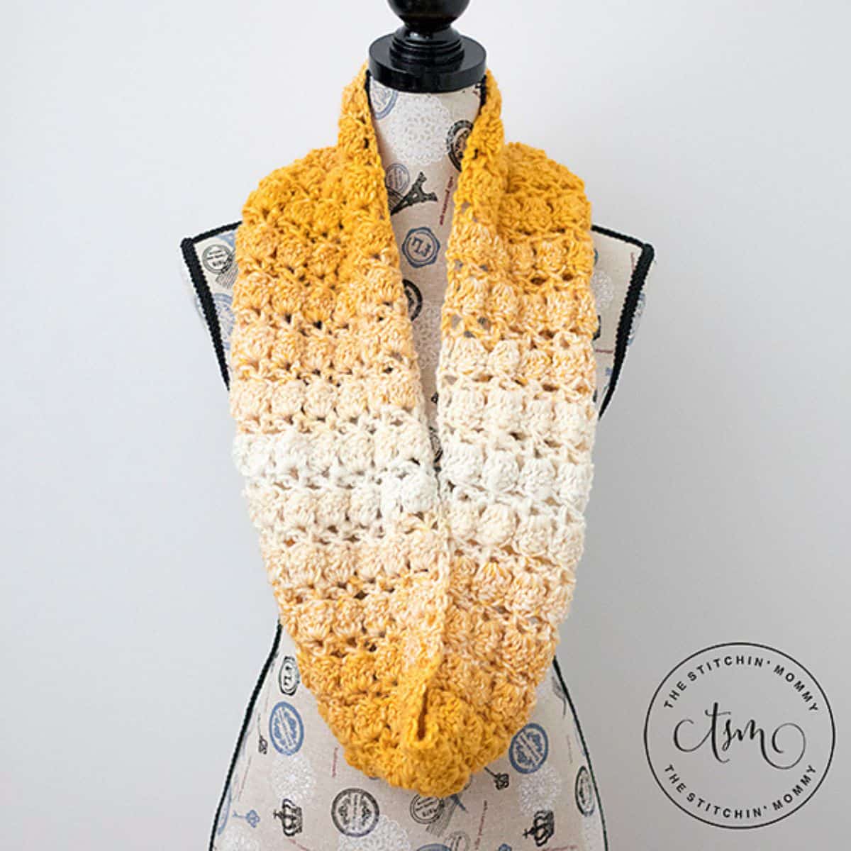yellow and white crochet scarf displayed on a mannequin