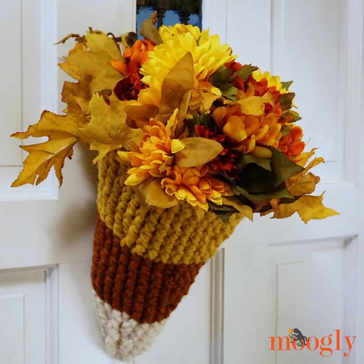 crochet candy corn basket filled with flowers and hanging on a door