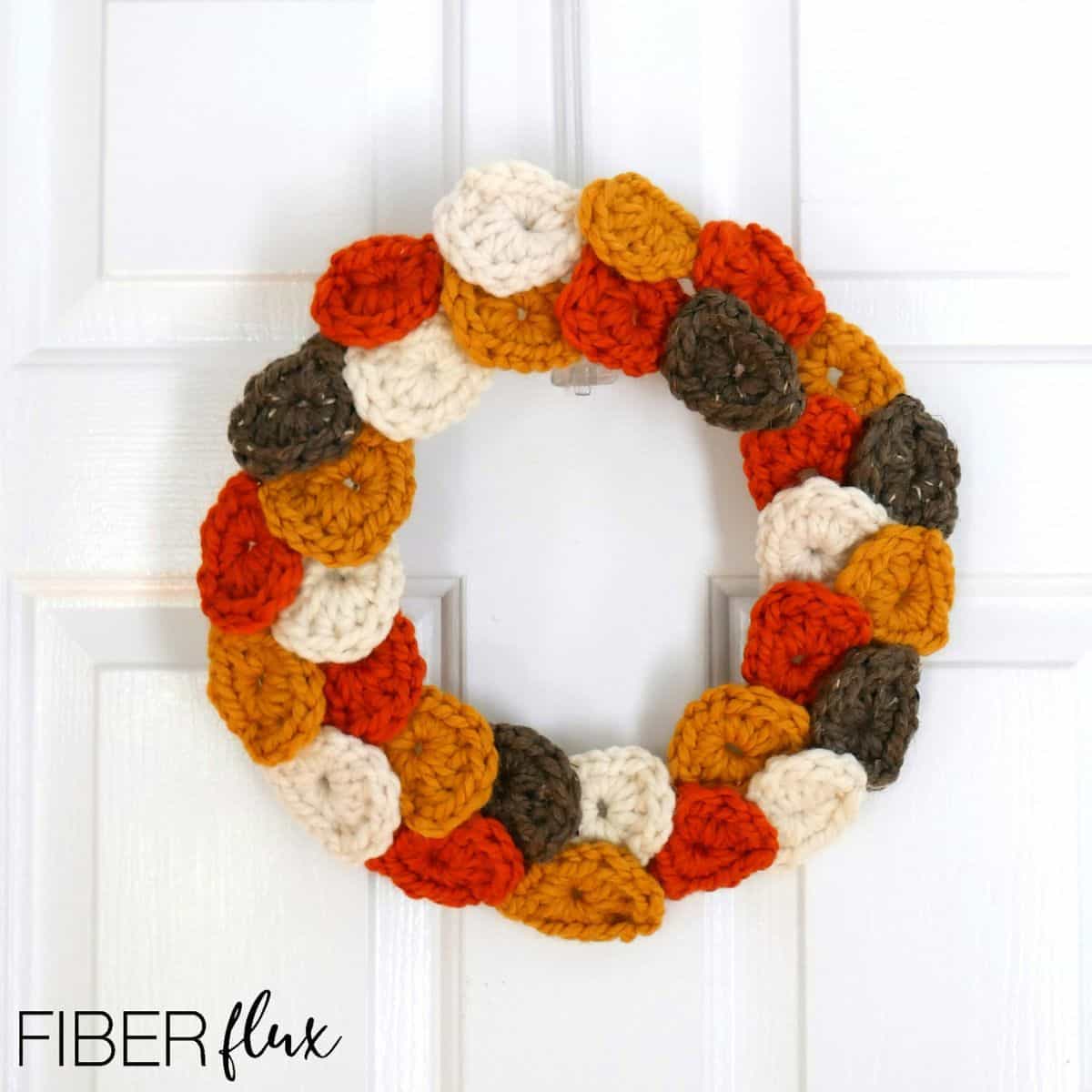 crochet fall leaves wreath hanging on a door