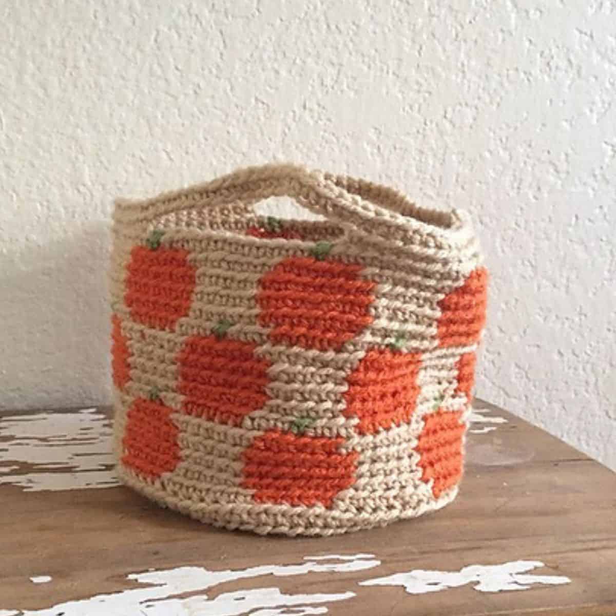 crochet basket with pumpkin motifs sitting on a table