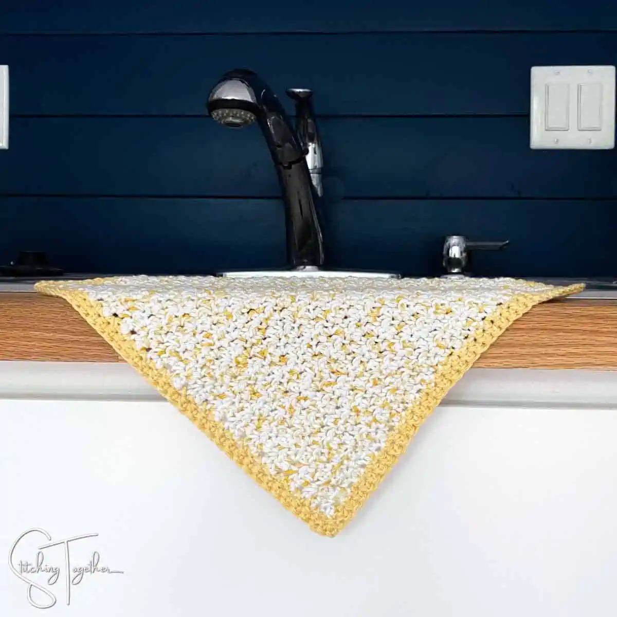 yellow and white crochet dishcloth draped on the edge of a sink