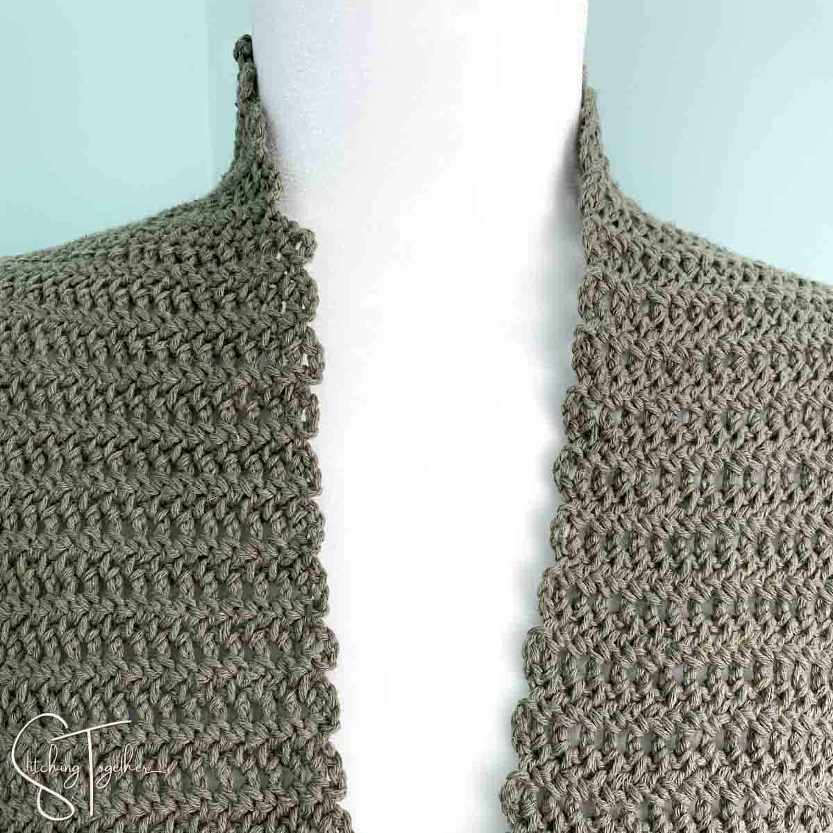 close up of green crochet scarf on a mannequin