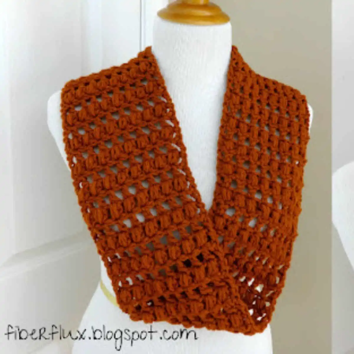 burnt orange crochet scarf on a mannequin