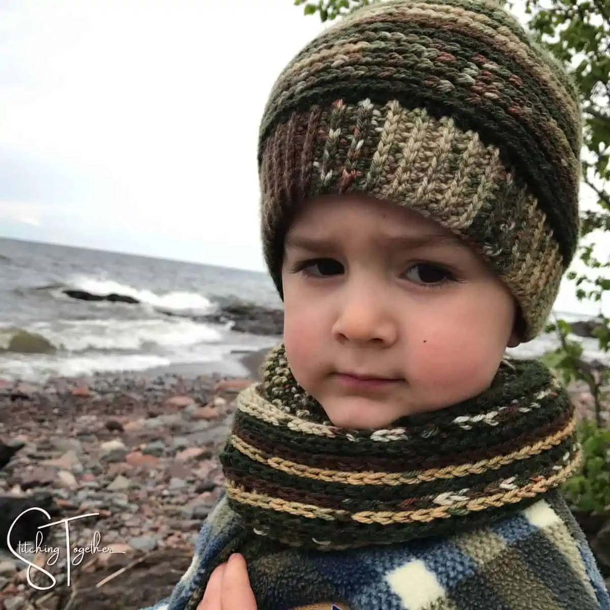 little boy wearing a matching crochet hat and scarf set
