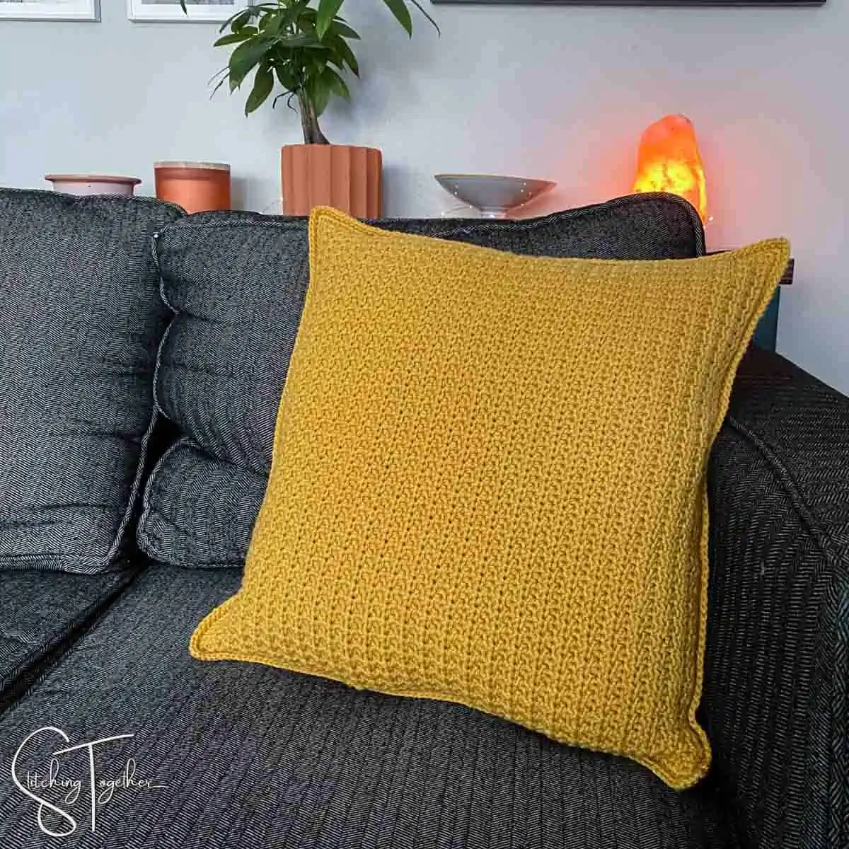 textured crochet pillow sitting on a couch