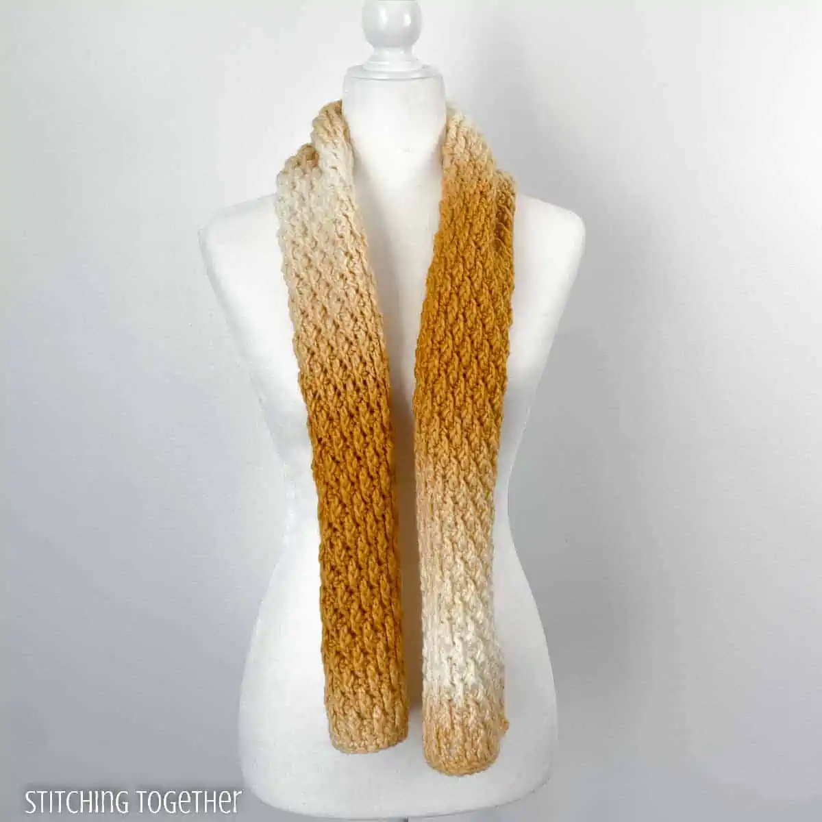 yellow and white textures scarf draped on the neck of a mannequin