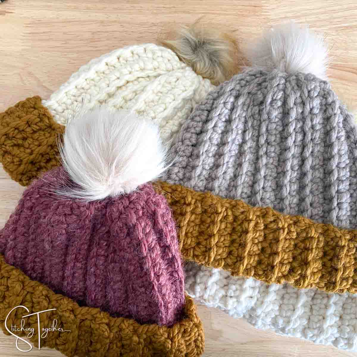 pile of crochet hat with faux fur pom poms