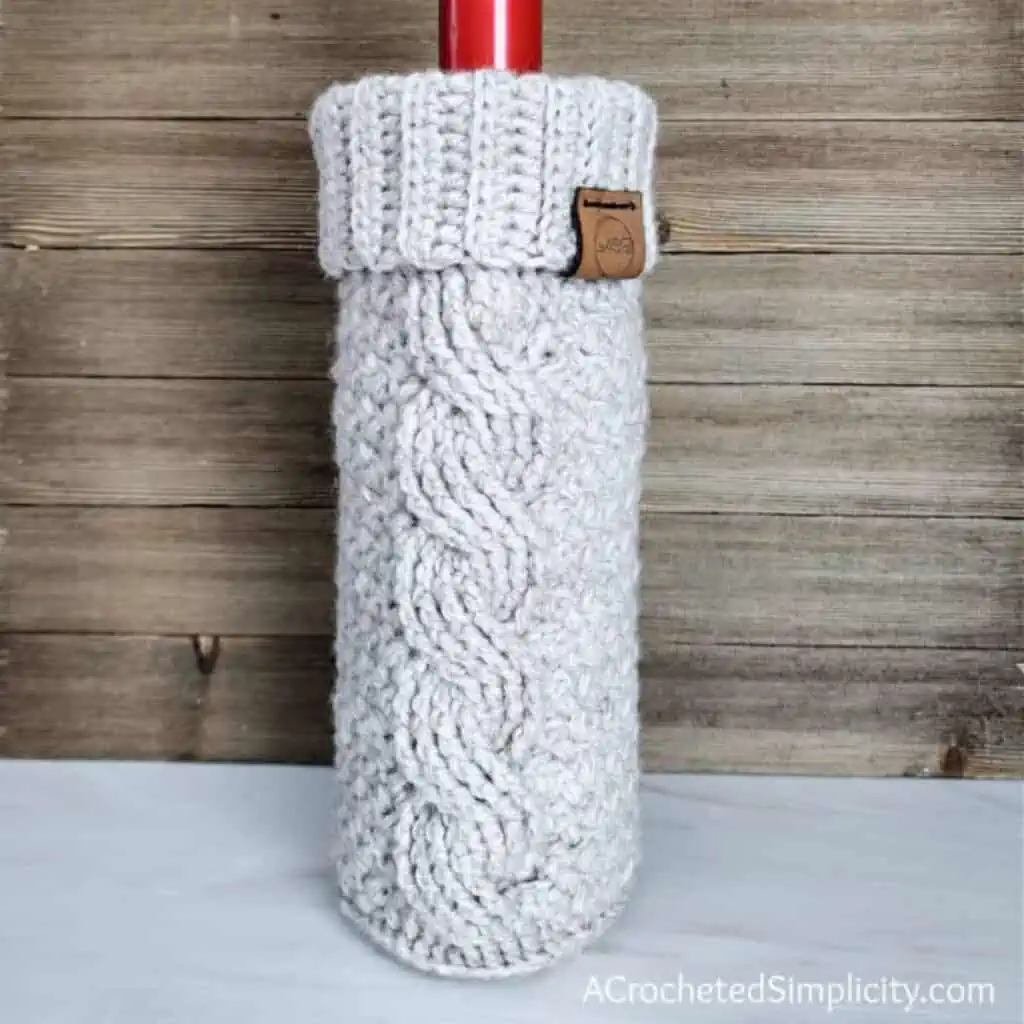 cabled crochet wine cozy around a bottle of wine