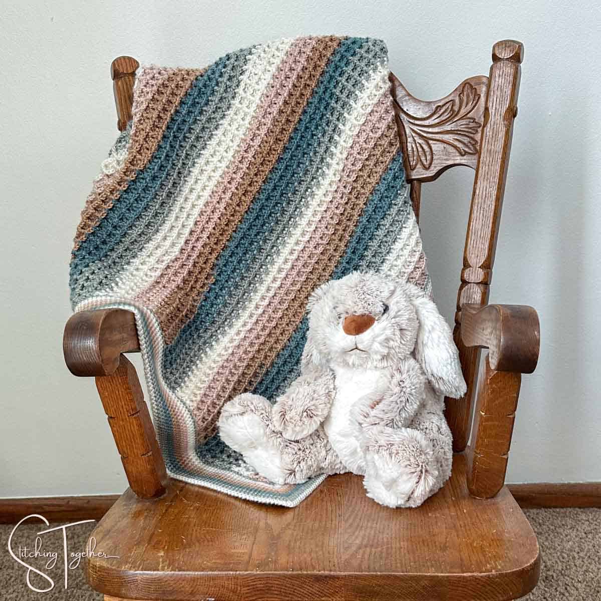 small rocking chair with a waffle baby blanket draped on the back and a stuffed bunny sitting in the chair