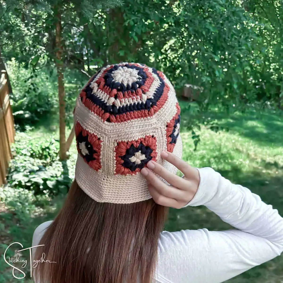 woman wearing a colorful crochet bucket granny square hat viewed from the back