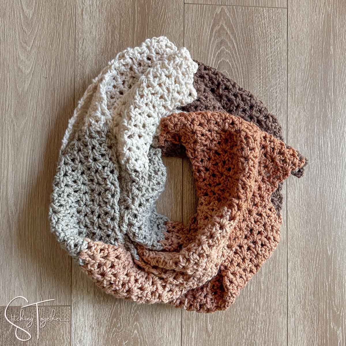 crochet v stitch scarf with multiple colors laid in a circle on the floor