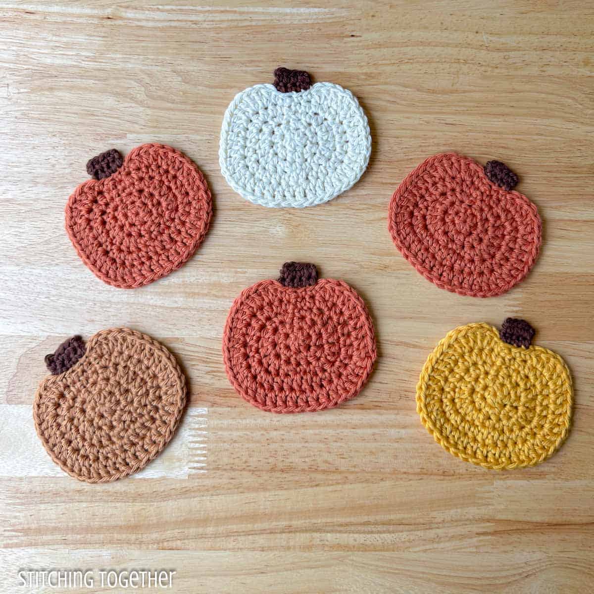 six cute crochet pumpkins laying flat spread out on a table