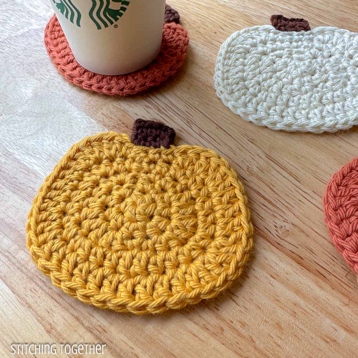 close up of crochet pumpkin with a disposable cup sitting on an orange crochet pumpkin coaster