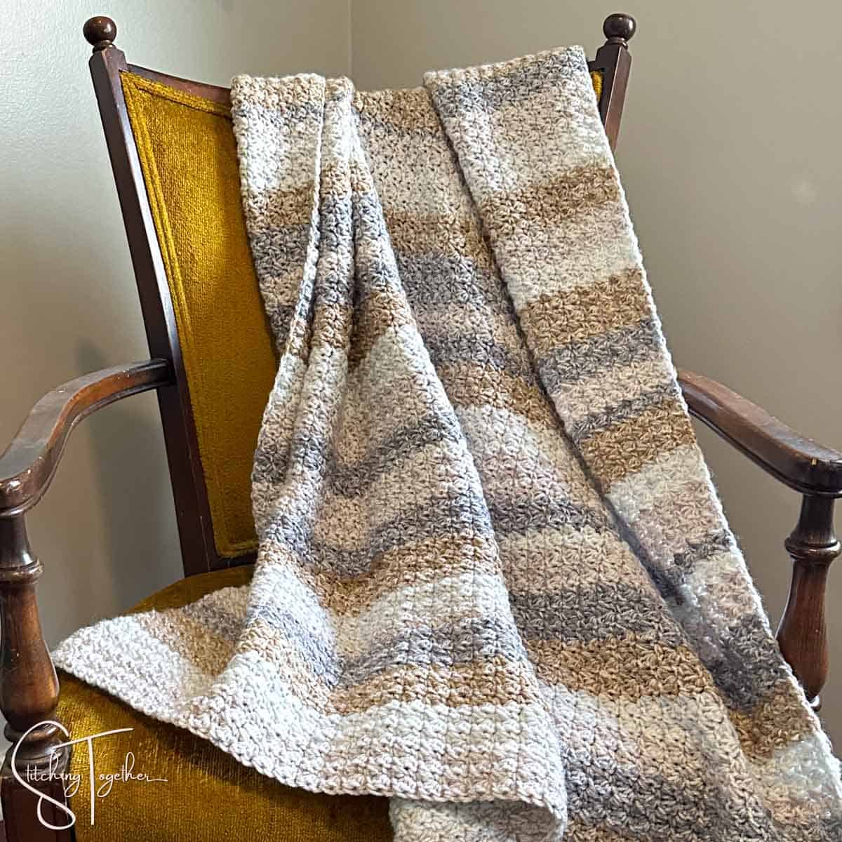 striped crochet blanket draped on a yellow chair